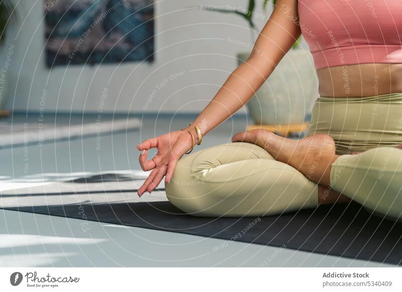 Crop woman meditating with Gyan mudra hands yoga meditate studio padmasana lotus pose practice zen mindfulness female mat calm session harmony stress relief