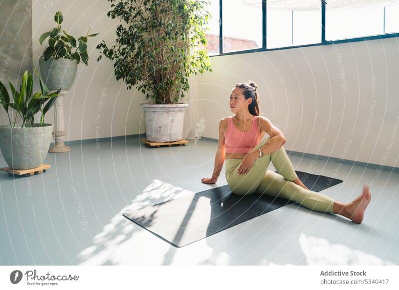 Relaxed woman doing Sage Marichi III pose on mat yoga asana sage marichis iii balance calm meditate practice mindfulness zen harmony healthy asian ethnic