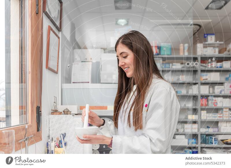 Happy woman grinding medical preparation during work in drugstore prepare pharmacist mortar pestle medicine pharmacy smile positive ingredient female