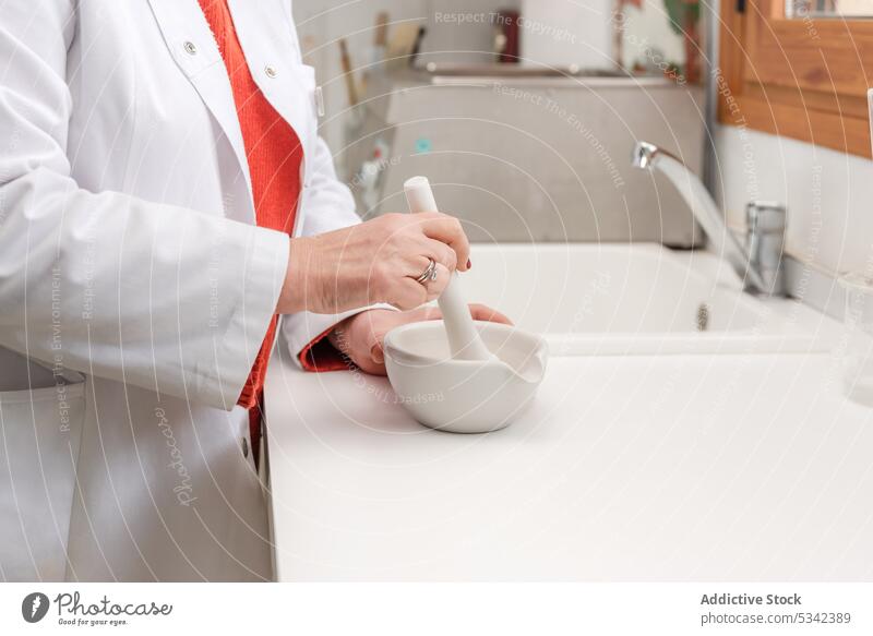 Doctor in medical uniform using mortar and pestle during medical preparation woman pharmacist prepare grind ingredient medicine process specialist equipment