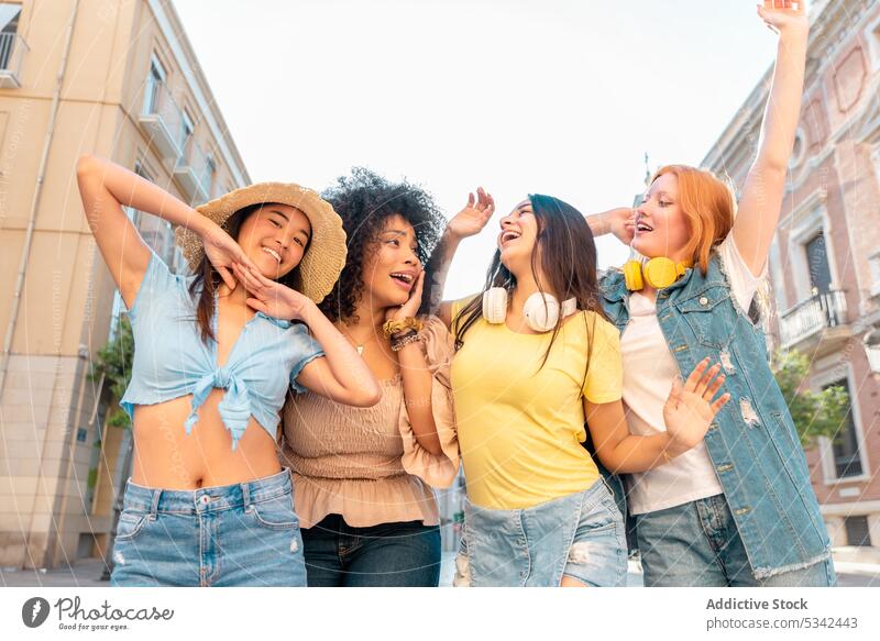 Happy diverse girlfriends walking along street women together stroll enjoy cheerful happy friendship city free time multiethnic multiracial young female spain