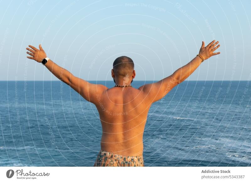 Anonymous calm man with raised arms against endless sea enjoy relax trip vacation freedom carefree beach summer nature sunset male puerto escondido oaxaca