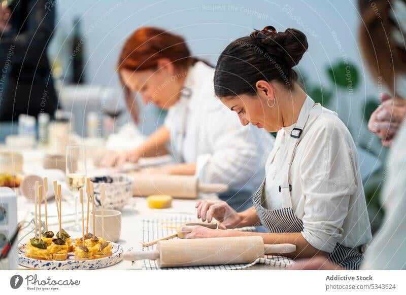 Focused women making clay products during class in studio pottery together rolling pin artisan prepare handmade crockery create ceramic workshop young skill