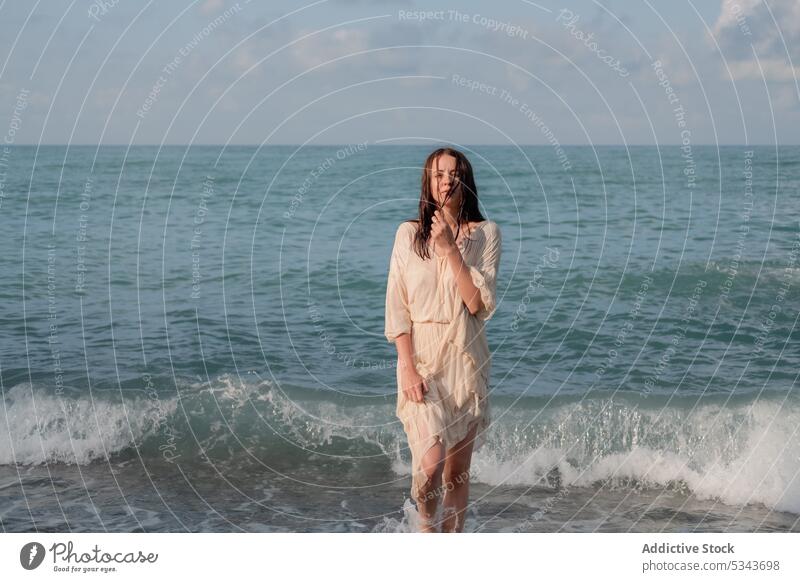 Woman looking at camera against cloudy sky during summer vacation woman sea swim calm tranquil resort holiday blue sky wet young recreation carefree serene