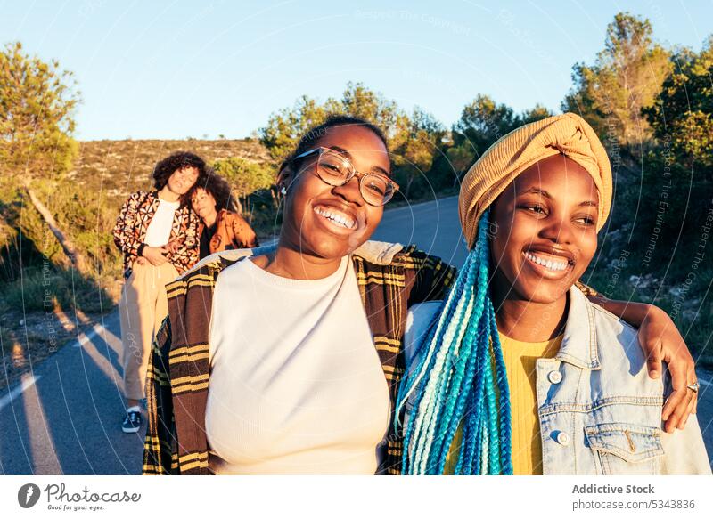 Happy black friends walking on roadside in daylight women friendship street spend time cheerful positive content glad female happy bonding outfit enjoy