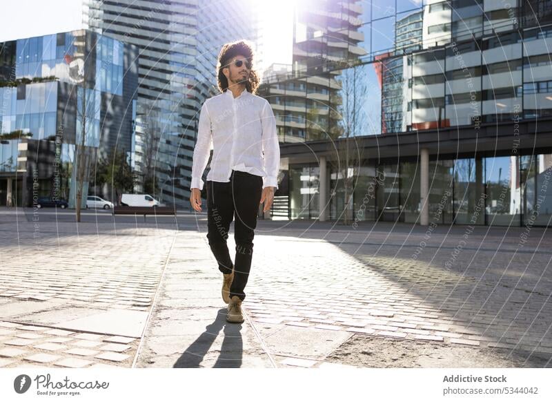 Ethnic man walking in the city street confident pensive afro gadget ethnic male african american black modern casual style using urban device serious black man