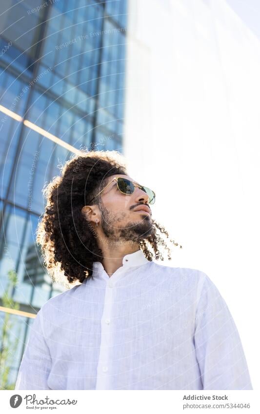 Ethnic man standing on the street and looking away style city outfit trendy serious curly hair pensive individuality ethnic black african american male urban