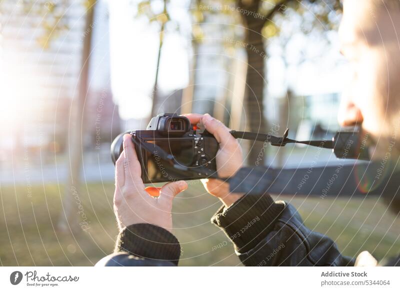 Crop photographer taking photo on camera in daylight outdoors man photo camera take photo person street city apartment moment sunlight photography gadget