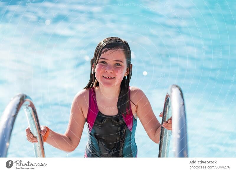 Smiling girl looking at camera in swimming pool summer resort vacation smile holiday swimwear happy water swimsuit kid child sun poolside recreation summertime