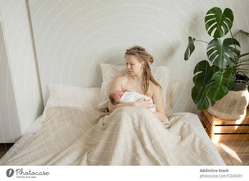 Mother breastfeeding newborn on bed woman mother baby infant mom childcare maternal cozy female comfort innocent motherhood together bedsheet lady peaceful