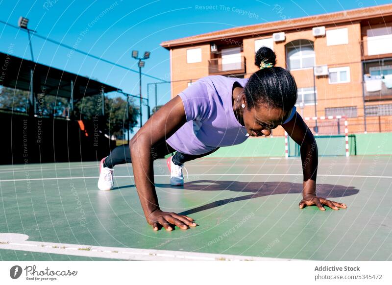 Strong black female athlete doing push ups during outdoor training sportswoman workout exercise sports ground determine stamina fitness healthy lifestyle adult