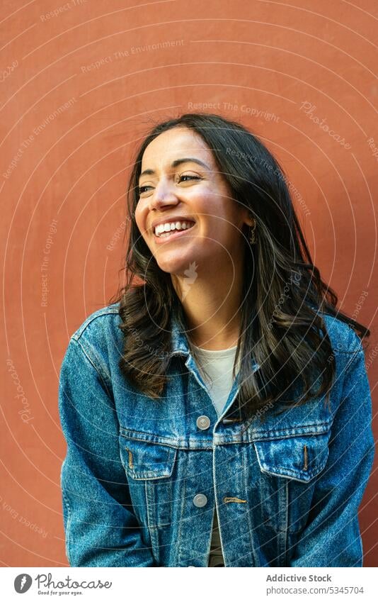 Cheerful young ethnic woman standing near orange backdrop portrait smile cheerful positive denim glad jacket delight dark hair happy female fashion hispanic