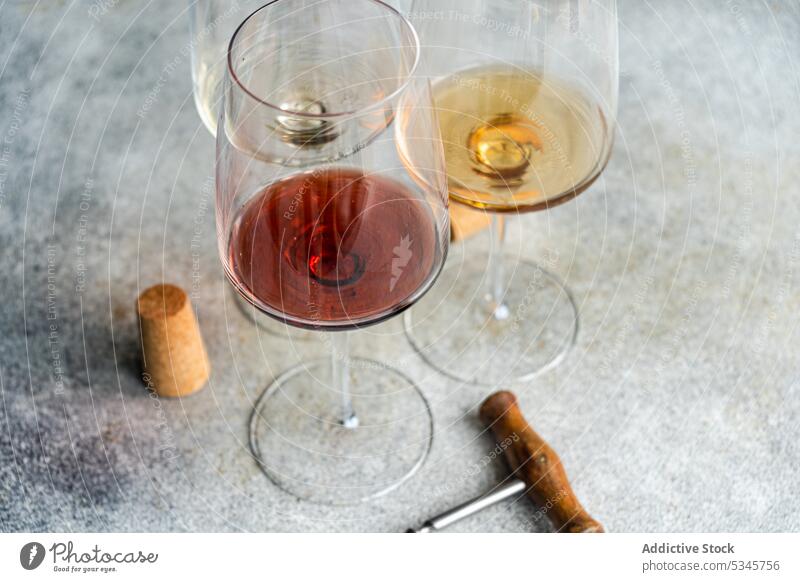 High angle of three main varieties of Georgian dry wines - white, red and amber on concrete grey table with a corkscrew and a cork Kisi alcohol background