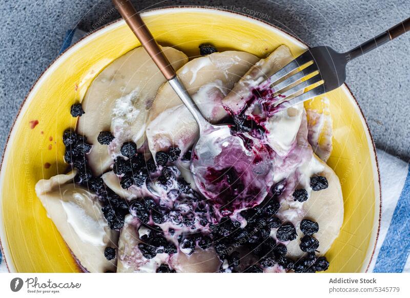 Tasty traditional Ukrainian dumplings background berry blueberry boiled bowl ceramic cutlery dough dessert dish dressing food fork spoon fresh gourmet jam lunch