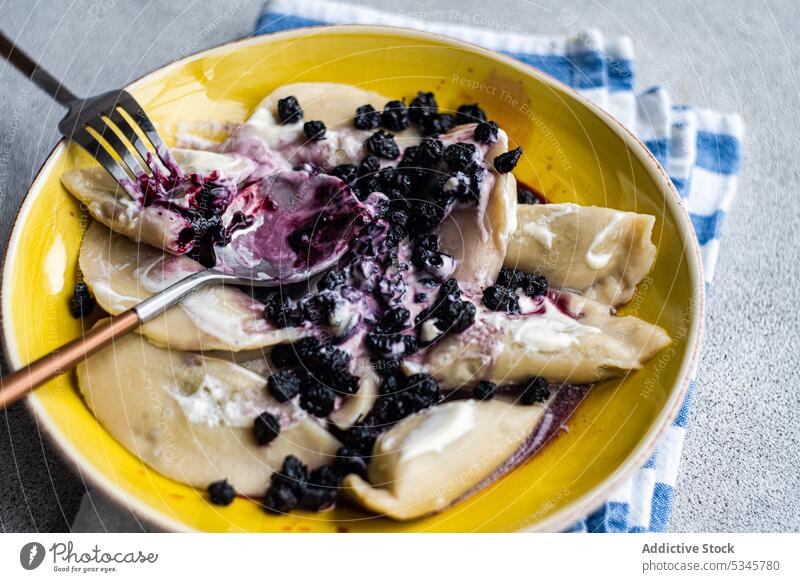 Tasty traditional Ukrainian dumplings background berry blueberry boiled bowl ceramic cutlery dough dessert dish dressing food fork spoon fresh gourmet jam lunch