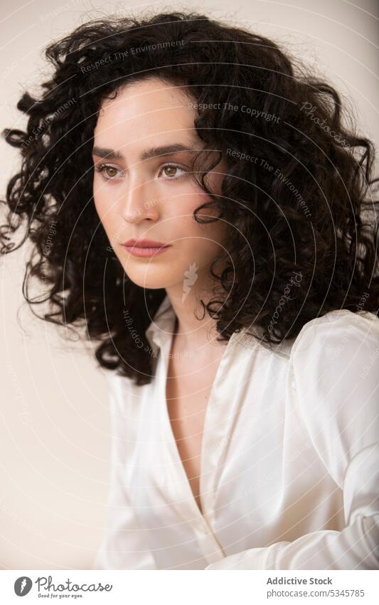 Pensive woman with curly hair against white background portrait pensive serious calm thoughtful appearance studio shot young female model style shirt