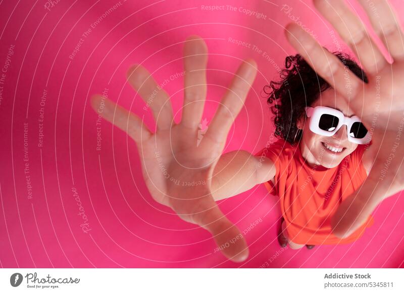 Funny stylish woman showing palms over pink background frame gesture style sunglasses smile happy sign cheerful elegant positive symbol optimist young female