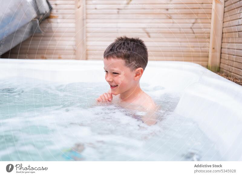 Little boy relaxing in hot bathtub in bathroom smile enjoy foam summer weekend recreation child kid childhood bubble cheerful vacation happy rest little