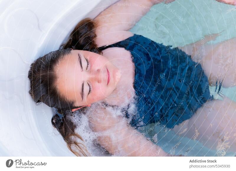 Girl resting in bathtub during summer day girl relax water recreation pleasure swimsuit leisure wellbeing pool chill spa resort lying swimwear wet enjoy female