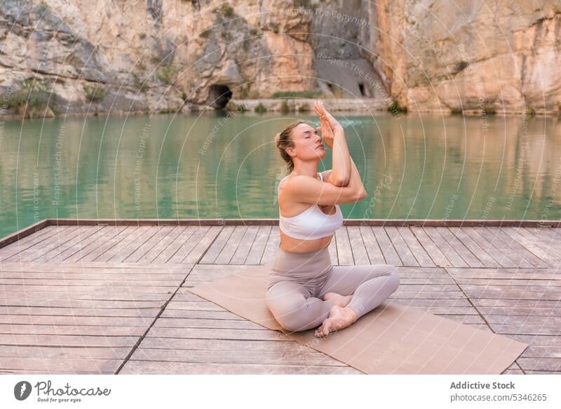 Fit woman practicing yoga on pier calm practice zen healthy asana harmony wellness meditate lake mountain pose female eagle pose garudasana lifestyle balance