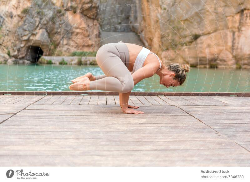 Flexible woman doing Crane pose fit flexible yoga practice asana crane pose balance Charco Azul Spain wellness harmony lake mountain nature wellbeing female