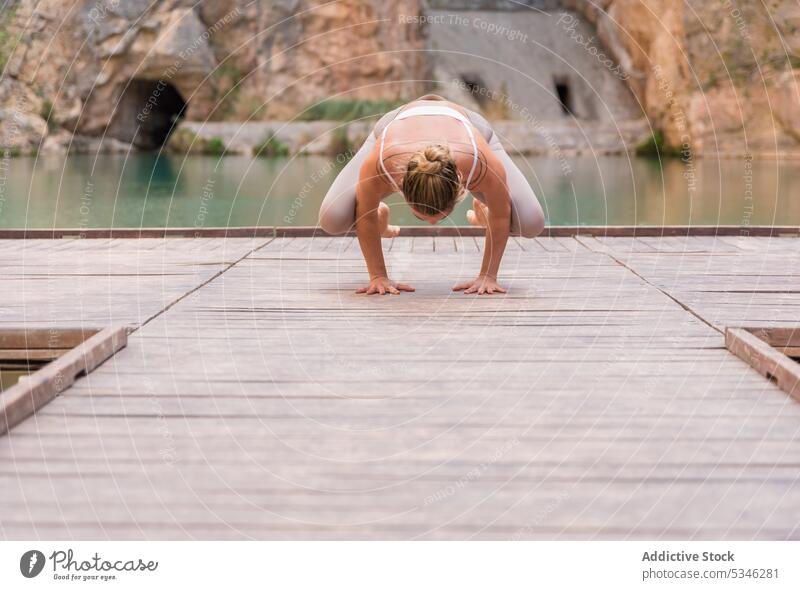 Flexible woman doing Crane pose fit flexible yoga practice asana crane pose balance Charco Azul Spain wellness harmony lake mountain nature wellbeing female