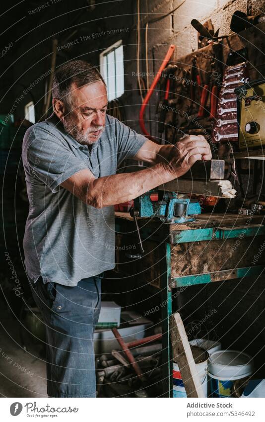 Aged carpenter using plane and working in garage man plank wooden workshop woodwork carpentry tool jointer male joinery craftsman timber lumber workbench