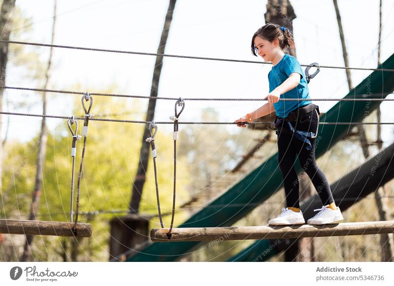 Girl balancing on wooden log in rope park girl balance safety concentrate child summer equipment nature activity childhood preteen kid entertain active focus