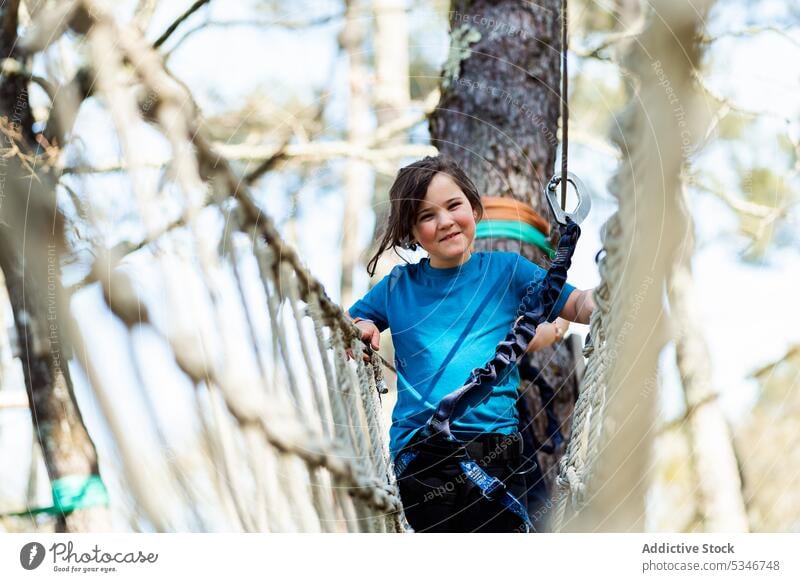 Happy girl balancing on rope swing in park child playground active equipment nature safety childhood activity happy summer entertain having fun kid playful