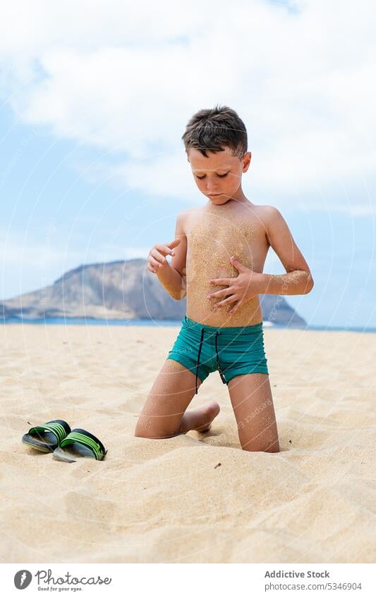 Little boy sitting on sandy beach sea wet resort kid coast child seashore summer seaside shirtless water summertime pleasure childhood nature seacoast coastline