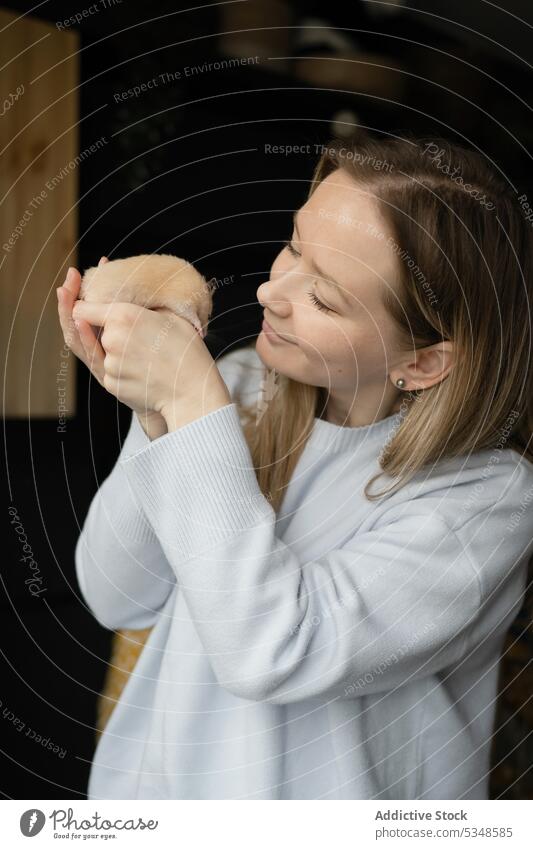 Young woman holding small hamster in hands pet owner domestic companion interior dark room young female calm affection lady serene tender tranquil peaceful