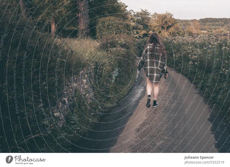 Girl in check shirt of a man walks across a dirt road young adult Shirt naked legs off the beaten track Landscape To go for a walk Walking amble Evening Small