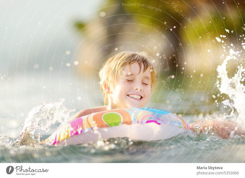 Little boy swimming with colorful floating ring in sea on sunny summer day. Cute child playing in clean water. Family and kids resort holiday during summer vacations.