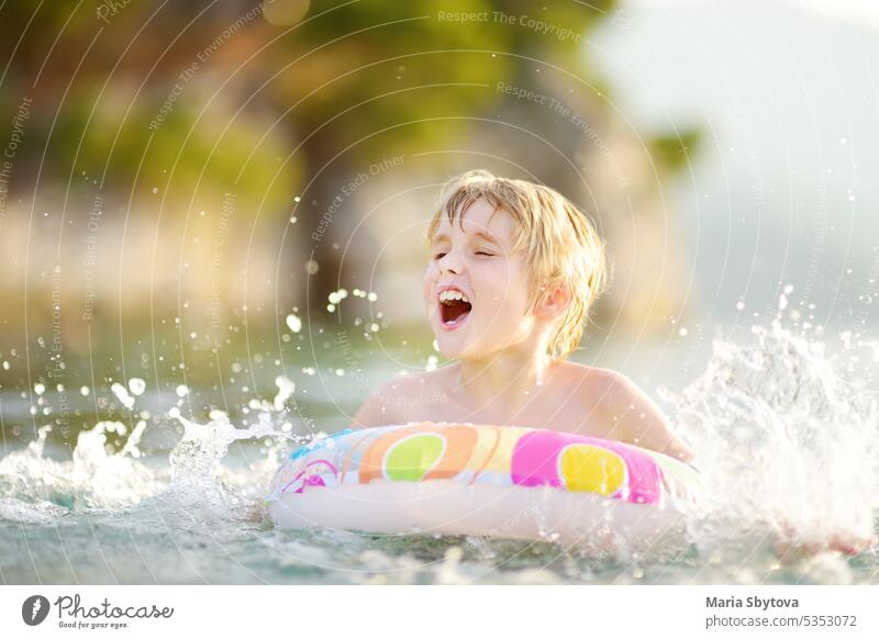 Little boy swimming with colorful floating ring in sea on sunny summer day. Cute child playing in clean water. Family and kids resort holiday during summer vacations.