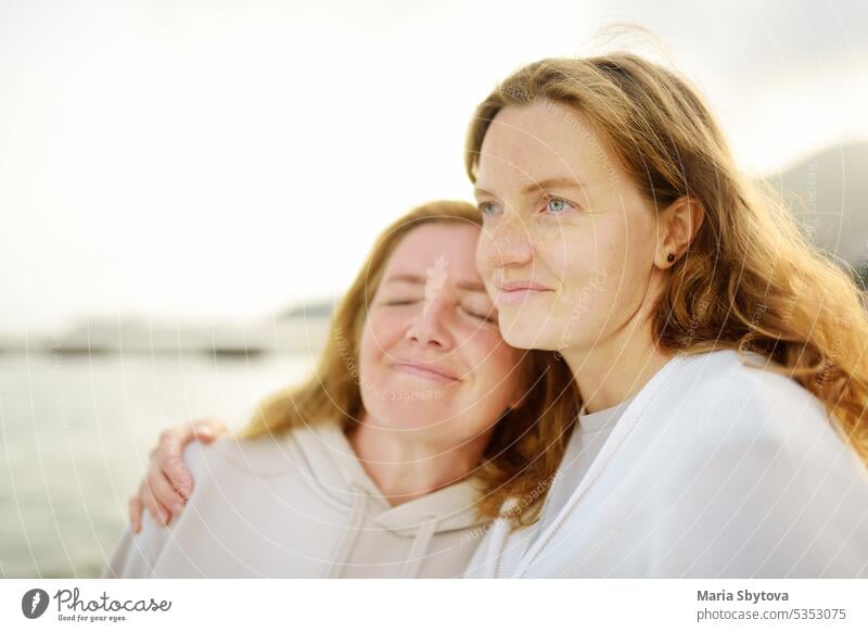 Redhead senior mother and her beautiful adult daughter are walking together and laughing grown up child family redhead look alike people portrait mom generation