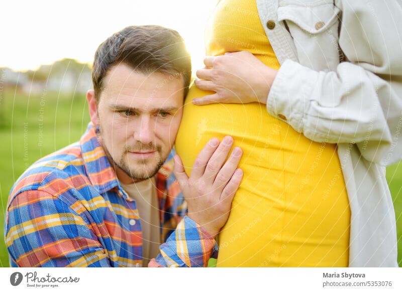 Young family is expecting a baby. Handsome man touching the belly of pregnant woman and feeling the movements of the child. future dad father couple girl tender