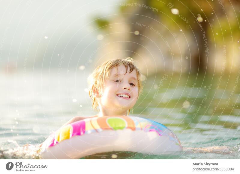 Little boy swimming with colorful floating ring in sea on sunny summer day. Cute child playing in clean water. Family and kids resort holiday during summer vacations.