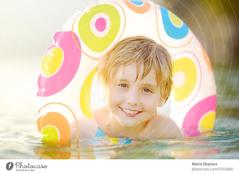 Little boy swimming with colorful floating ring in sea on sunny summer day. Cute child playing in clean water. Family and kids resort holiday during summer vacations.