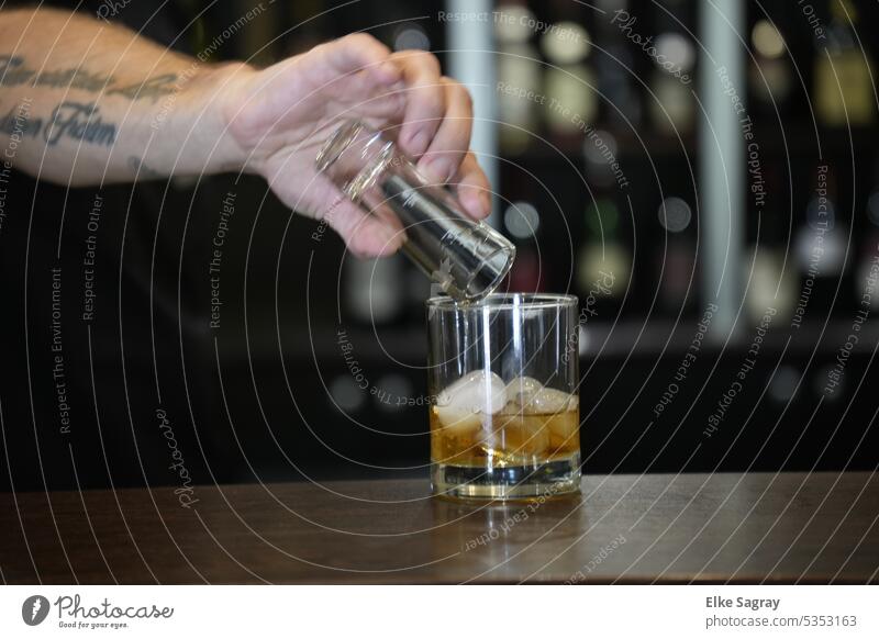 a scotch whiskey on the rocks is poured... Whiskey Glass Ice Cold Beverage Drinking Transparent Alcoholic drinks Dark Luxury arm Bar booze Bourbon Table cubes