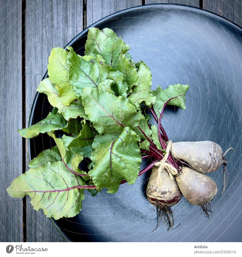 Vegetables | bunch of beet lies on a black plate on a wooden table Red beet Food Fresh Healthy Vegetarian diet Green Nutrition naturally Vitamin Nature Harvest