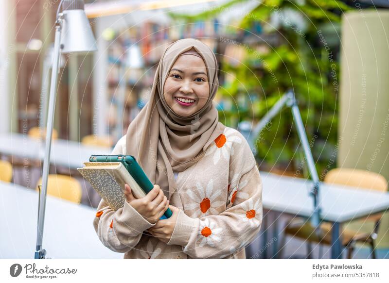 Portrait of asian muslim female student standing in a library real people teenager campus positive exam knowledge confident academic adult lifestyle academy