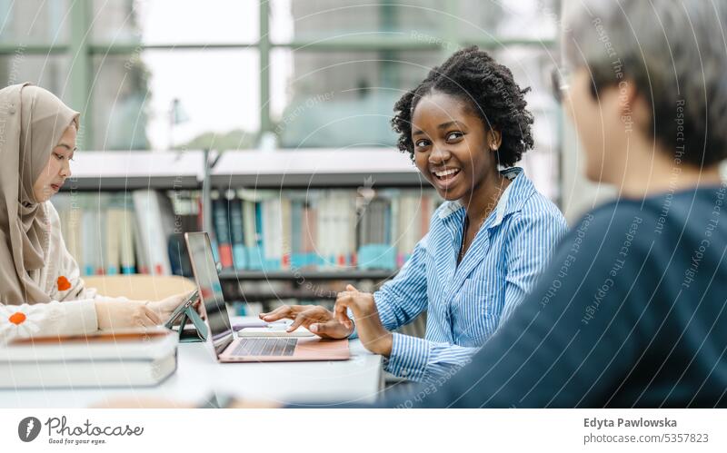 Multiethnic group of students sitting in a library and studying together real people teenager campus positive exam knowledge confident academic adult lifestyle