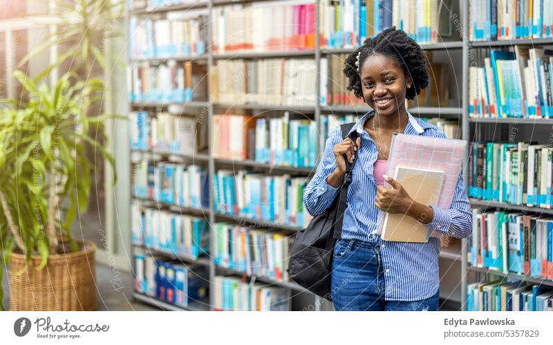 Portrait of black female student standing in a library real people teenager campus positive exam knowledge confident academic adult lifestyle academy adolescent