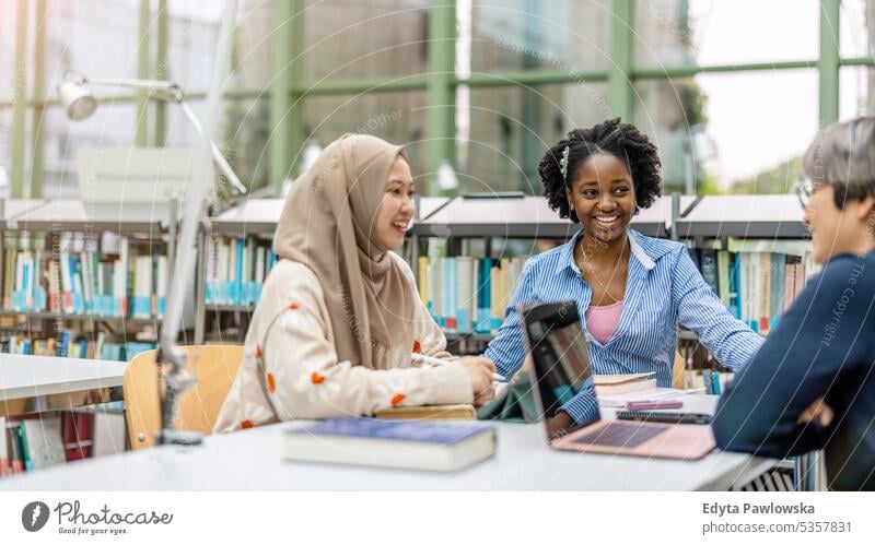 Group of multiethnic students having a discussion in a library real people teenager campus positive exam knowledge confident academic adult lifestyle academy