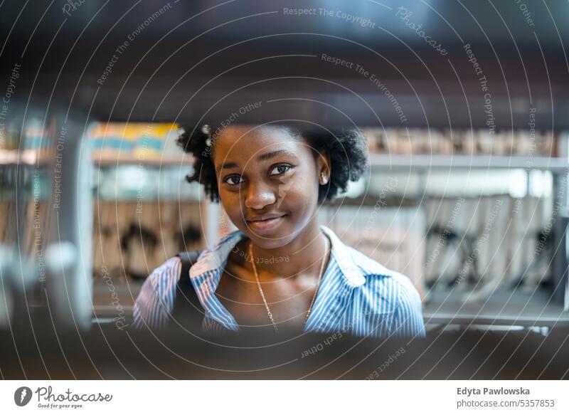 Portrait of black female student standing in a library real people teenager campus positive exam knowledge confident academic adult lifestyle academy adolescent