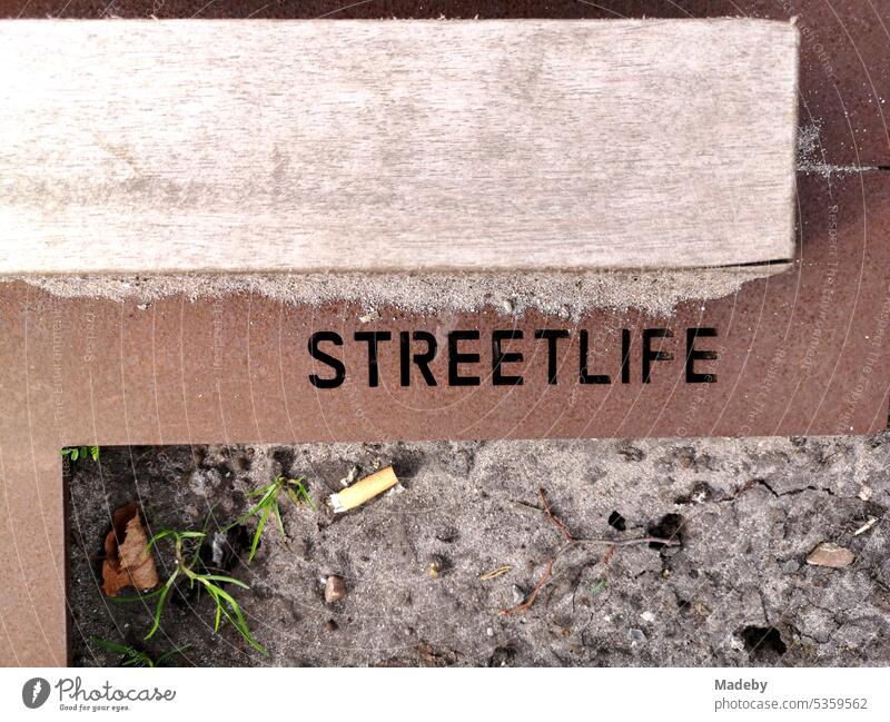 Edging of a flower bed made of rusty steel with the embossing Streetlife and cigarette butt on brown earth at the town hall square in Oerlinghausen near Bielefeld on the Hermannsweg in the Teutoburg Forest in East Westphalia-Lippe