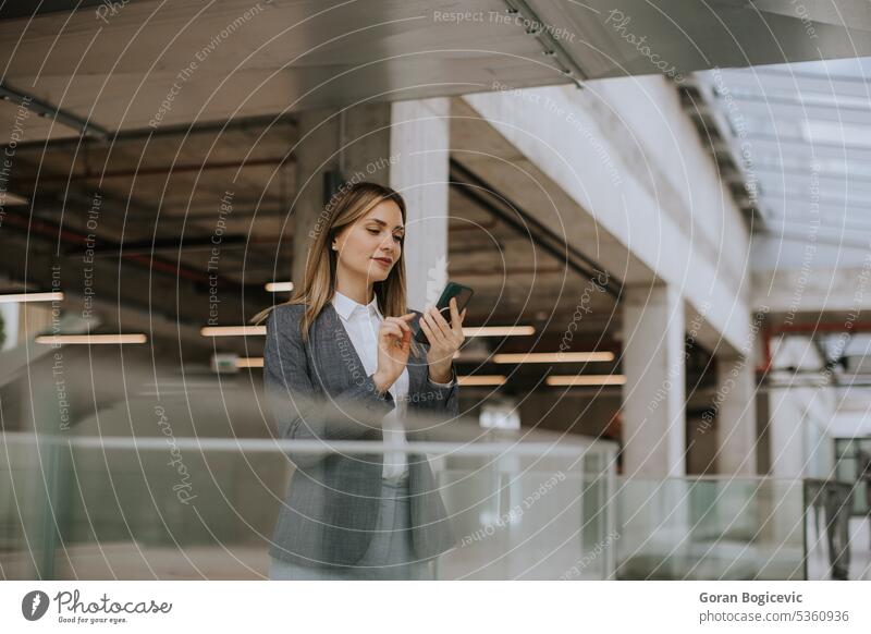 Young business woman using mobile phone in the office hallway caucasian professional businesswoman female people person confident talking cellphone