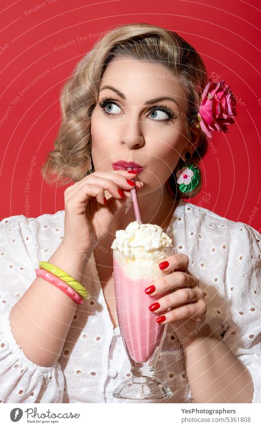 Woman drinking milkshake. Portrait of a retro style woman. 40s 50s background beauty beverage blonde blue eyes color concept curly curvy cute dress enjoy