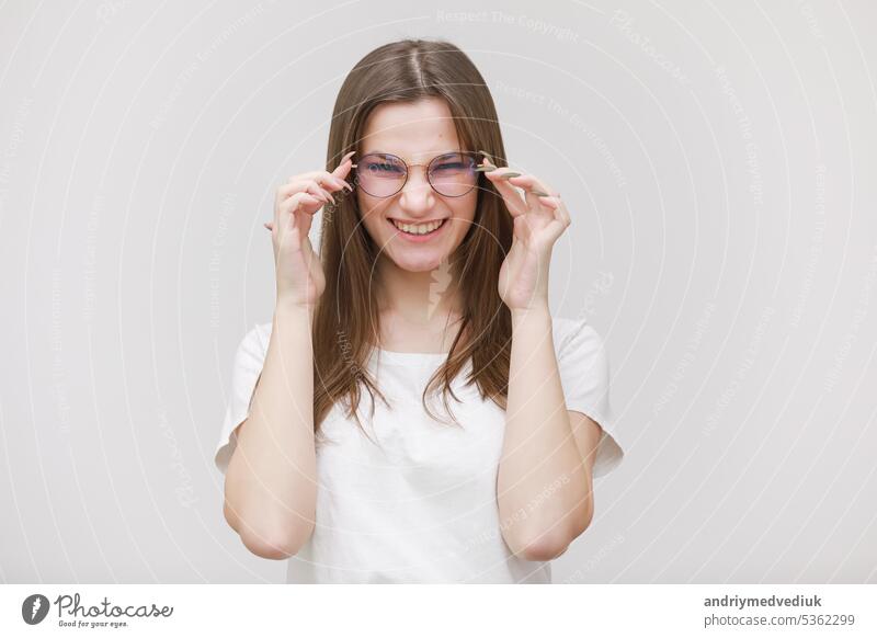 pretty teenage girl in glasses having fun on a white background. female in white t shirt with long hair in studio teenager lifestyle funny fashion beauty young