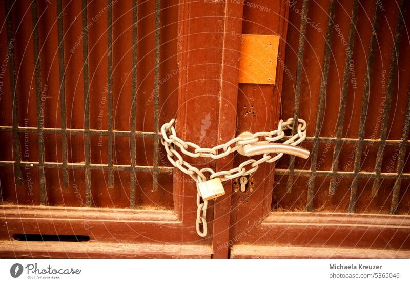 entrance door, double leaf brown wood, closed, steel chain secured with curtain lock, old weathered door lattice bars Architecture Colour photo Building